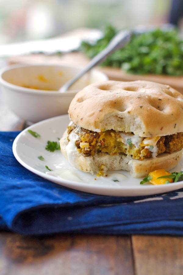 Curried veggie burger in a bun with a bite taken out.