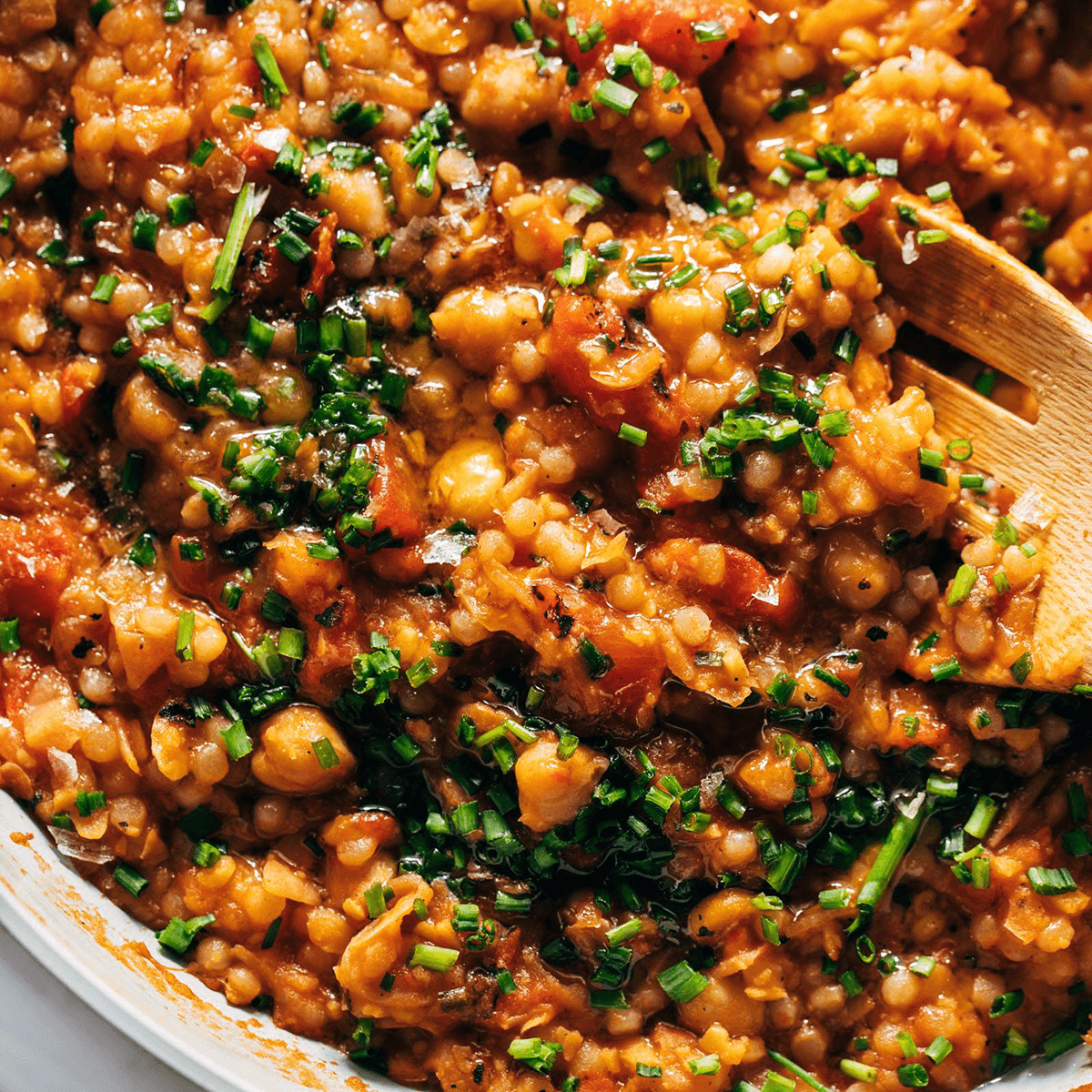 Pearl couscous in a skillet with tomatoes.