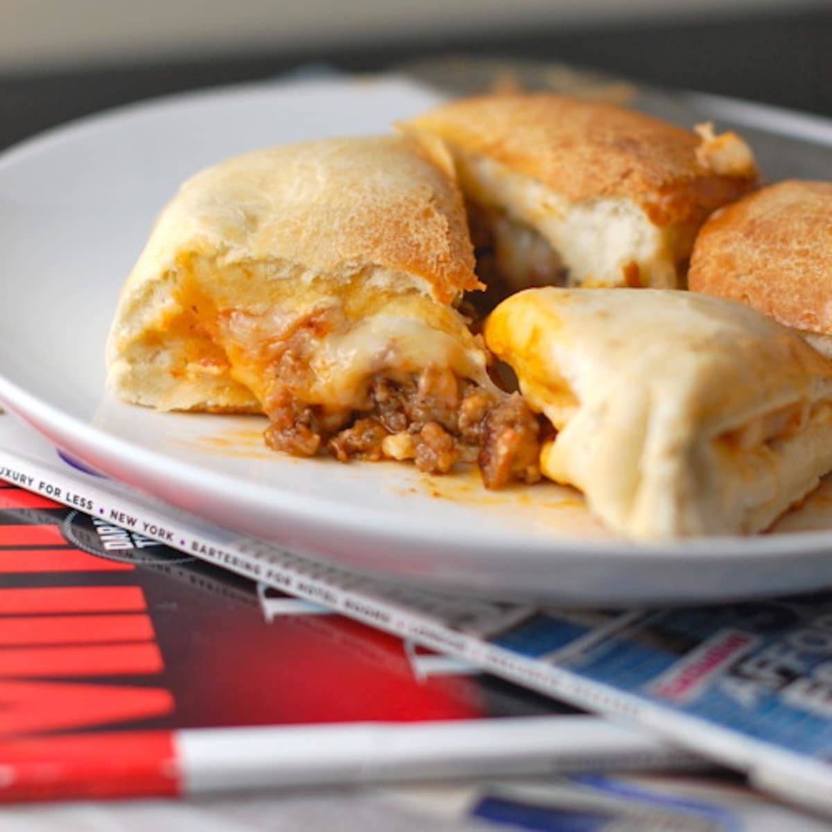 Sausage and mozzarella calzones on a white plate.