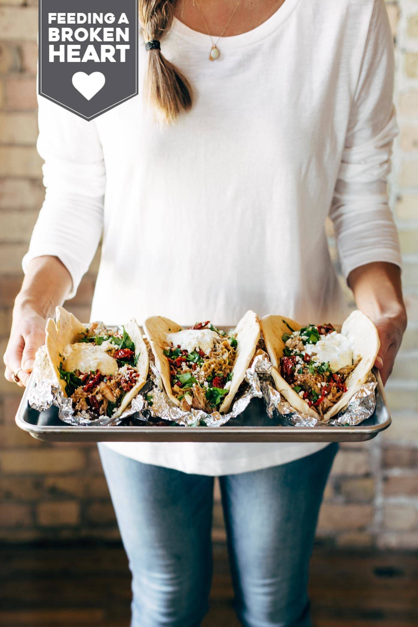 Everything Greek Pork Pitas - peppery pork with tzatziki, parsley, sun dried tomato, feta, and lemon juice. works in the Instant Pot! | pinchofyum.com Woman holding a tray of Everything Greek Pork Pitas.